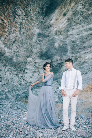 Beautiful couple near the rocks, looking with a smile at each other, hug, wedding dayの写真素材