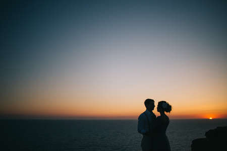 Beautiful sunset at sea, a man and a woman hold hands, look at each other, a love storyの写真素材