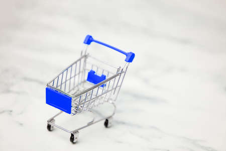 Shopping carts from supermarket on a light white background. Two empty stainless steel small miniature toy shopping trolley on marble table. shopping concept.の写真素材