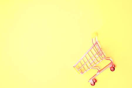 Empty shopping cart isolated on yellow background with copy space for text or design. Top view, flat lay of shopping trolley. Supermarket, shopping, sale concept.の写真素材