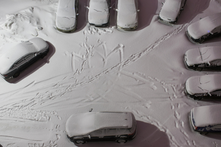 Vehicles standing at winter parking lot covered with snow, cars in night cityの写真素材