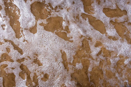 Lacy pattern of wave and sea foam rolling onto the shore.の写真素材