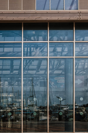 Abstract image of reflections of boats and masts in the marina's glass facade