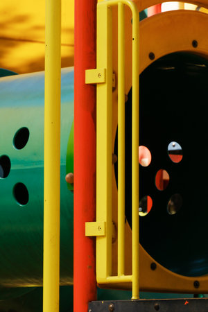 Colorful playground tunnel structure with metal bars and vibrant design.
