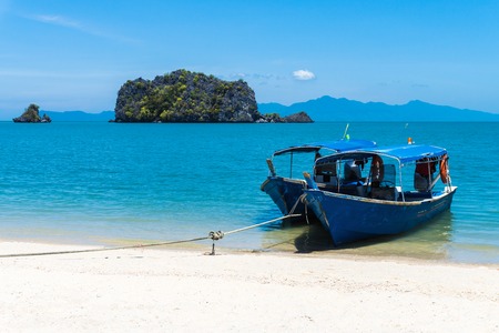 Old wooden walking boats that tied the rope on the shore on the tropical beach in Malaysiaの写真素材
