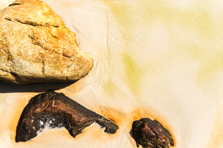 Small sea rocks scattered on beach sand close up. Background with copy space.の写真素材