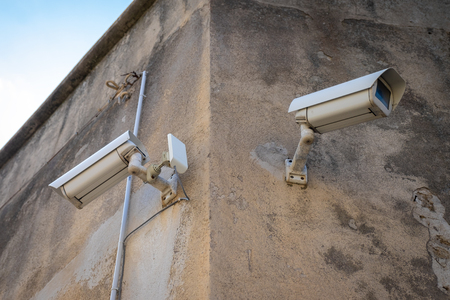 CCTV security cameras on pole on building corner watching the area