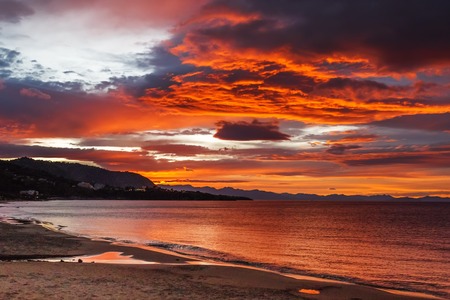 Beautiful colorful red sunset at the sea with dramatic cloudsの写真素材