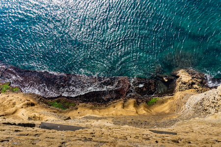 Aerial top view of sea waves hitting rocks on the beach with turquoise sea water. Amazing rock cliff seascape.の写真素材