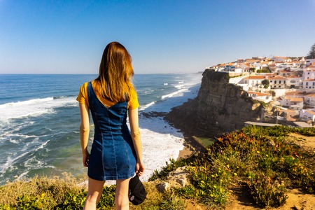 Young woman from back looking to Azenhas do Mar, located on the cliffs near Sintra, Portugal.の写真素材