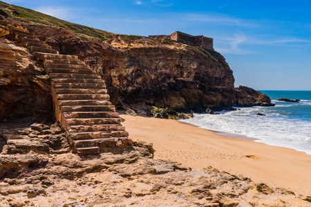 Stairs to the beach of the Atlantic Ocean at the lighthouse in the town of Nazare in Portugalの写真素材