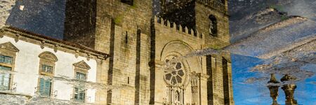 Reflexion of the catholic church in puddle in Porto, Portugal. Wide banner.