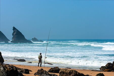 Atlantic ocean rocky coastline of Adraga beach with fisherman. Portugal rocky coastの写真素材