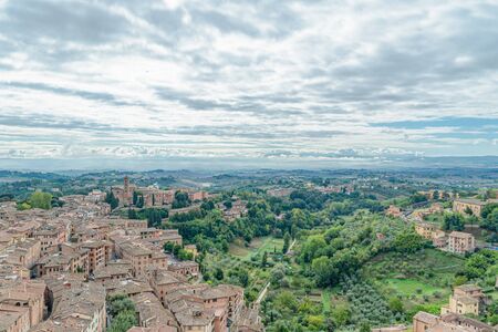 Beautiful aerial panoramic view of Old Town of medieval city of Siena in the cloudy autumn day, Tuscany, Italyの写真素材