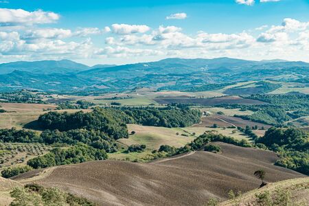Aerial view of a rural landscape in Tuscany. Rural farm, vineyards, cypress trees, sunlight and clouds. Italy, Europe.の写真素材
