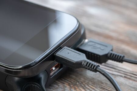 Mobile smart phones charging on wooden desk. Phone Connected to usb chargerの写真素材