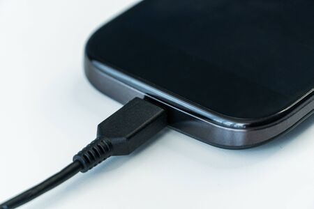 Smartphone charging with power bank on wood board. Phone Connected to chargerの写真素材