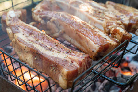 Barbecue pork spare ribs cooking on a grill outdoors in summer with selective focusの写真素材
