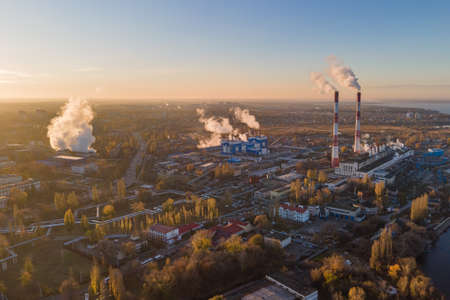 Aerial view of cityscape with industrial enterprises and emission of harmful smoke from the chimneys