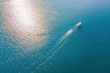 Sailboat in the sea. White sailing yacht in the middle of the boundless ocean. Aerial view.