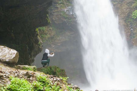 Young woman take photo of waterfall. People travel enjoying nature, break from city