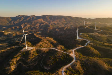 Windmills farm for power production on beautiful landscape at sunrise. Wind power turbines generating clean renewable energyの写真素材