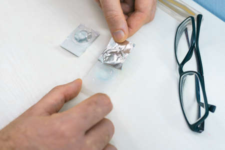 Man take contact lenses from holding plastic container. Vision correction of myopia, hyperopia...