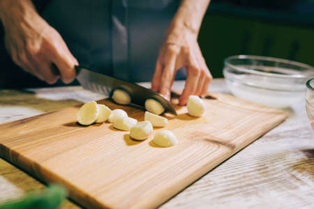 Woman cutting cheese Mozzarella for cooking salad at kitchen, prepare healthy mealの写真素材