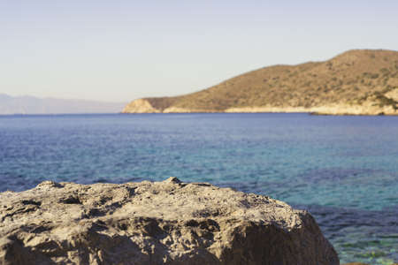 Pedestal or podium Stand for Exhibit, natural Stone like podium with background of sea coast of Greeceの写真素材