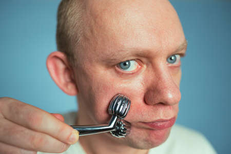 Man getting massage of face using face roller. Facial skin care lifting and beauty conceptの写真素材