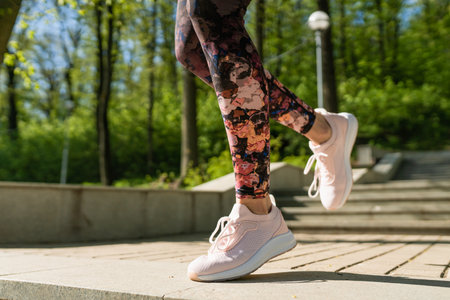 Young woman runs up the stairs in the park. Active female outdoors in summer morning
