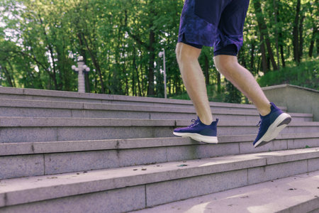 Man athlete legs running up stairs training intense cardio work out exercise, male runner feet jogging in city parkの写真素材