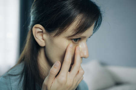 Woman applying under eye patch at home doing a skincare beauty routine product applicationの写真素材