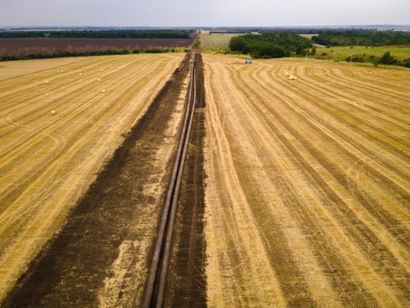 Open oil pipeline exposed that is under construction on agricultural field. Aerial viewの写真素材