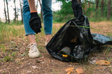 Cleaning plastic in forest. Volunteer collect trash in a trash bag. Plastic pollution and environmental problem concept.の写真素材