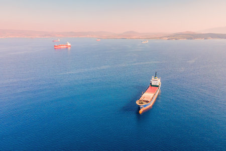 General cargo vessel or bulk carrier anchored at sea nearby port awaiting loading, Aerial...