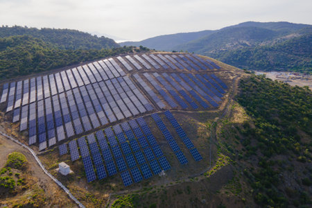 Aerial view of Solar power station panels in a row in mountain landscape at sunsetの写真素材