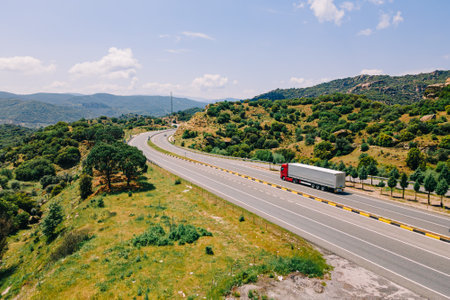 Semi-trailer truck speeds along the highway running across mountains, aerial tracking shotの写真素材