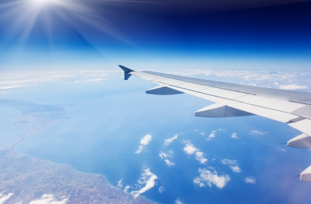 Wing of airplane flying above the clouds in the skyの写真素材