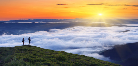 A photographers takes pictures fog from the top of mountain