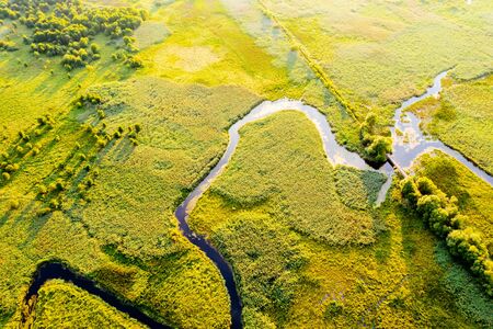 Aerial drone view of winding river in green field. Lush wetlands of bird's eye view. Location place countryside of Ukraine, Europe. Textural image of drone photography. Discover the beauty of earth.の写真素材