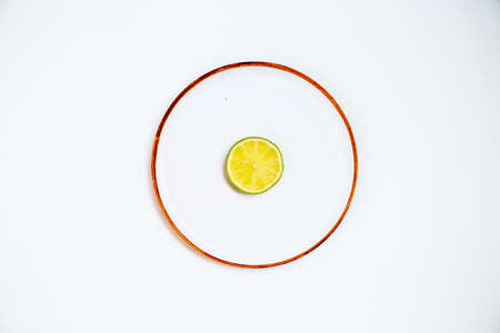 Lime fruits on plate isolated on white background. Natural organic product. Symmetrical arrangement, flat lay styling. Top view. Creative still life idea of spring wallpaper. Art photography concept.の写真素材