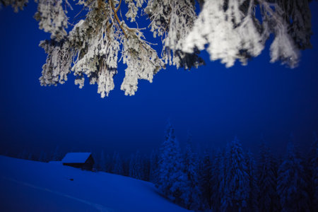 Fantastic winter landscape with a wooden hut in the dark forest. Location place Carpathian mountains, Ukraine, Europe. Vibrant photo wallpaper. Christmas holiday concept. Discover the beauty of earth.の写真素材
