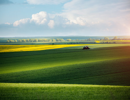 Tractor spraying pesticides on soybean field at springtime on a sunny day. Location place of Ukraine, Europe. Scenic image of agrarian industry. Photo of ecology concept. Beauty of earth.の写真素材