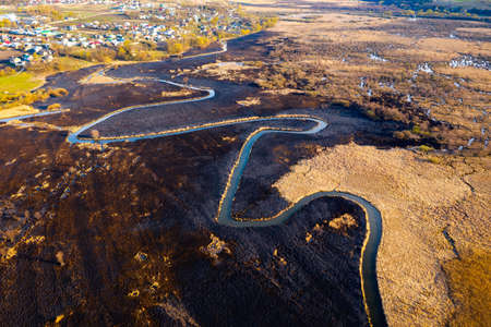 Aerial photography of the burning and scorched dry fields. Dry grass burns in the reserve. Natural disaster. The ground is covered with black ash after the fire. Top view drone shot. Beauty of earth.の写真素材