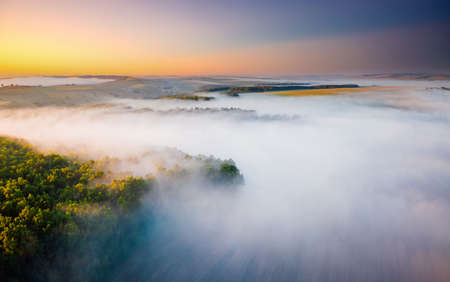 Peaceful misty view of the countryside with the rays of morning light. Location place Dniester canyon of Ukraine, Europe. Aerial photography, drone shot. Photo wallpaper. Discover the beauty of earth.の写真素材