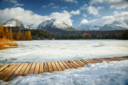 Winter landscape of a frozen mountain lake on a frosty sunny day. Location place Strbske pleso, High Tatras national park, Slovakia, Europe. Vibrant photo wallpaper. Discover the beauty of earth.の写真素材