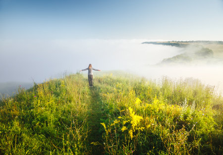 Carefree hipster girl enjoying nature on top of mountain. Image of freedom concept. Hiker during travel holidays vacation outdoors. Wonderful summertime wallpaper. Discover the beauty of earth.の写真素材