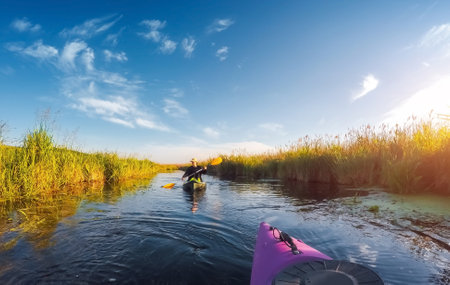 Carefree young woman enjoying kayaking down the river at dawn. Location Seret, Ukraine. Active recreation in the open air. Female is engaged in water sport on vacation. Discover the beauty of earth.の写真素材