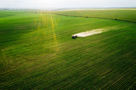 Scenic top view of a tractor spraying green fields. Organic irrigation field. Location place of Ukraine agrarian region, Europe. Aerial photography, drone shot. Industry of agronomy. Beauty of earth.の写真素材
